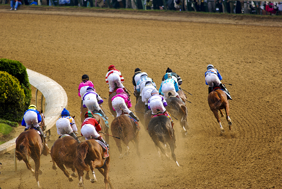 Horses racing with jockey's on racetrack