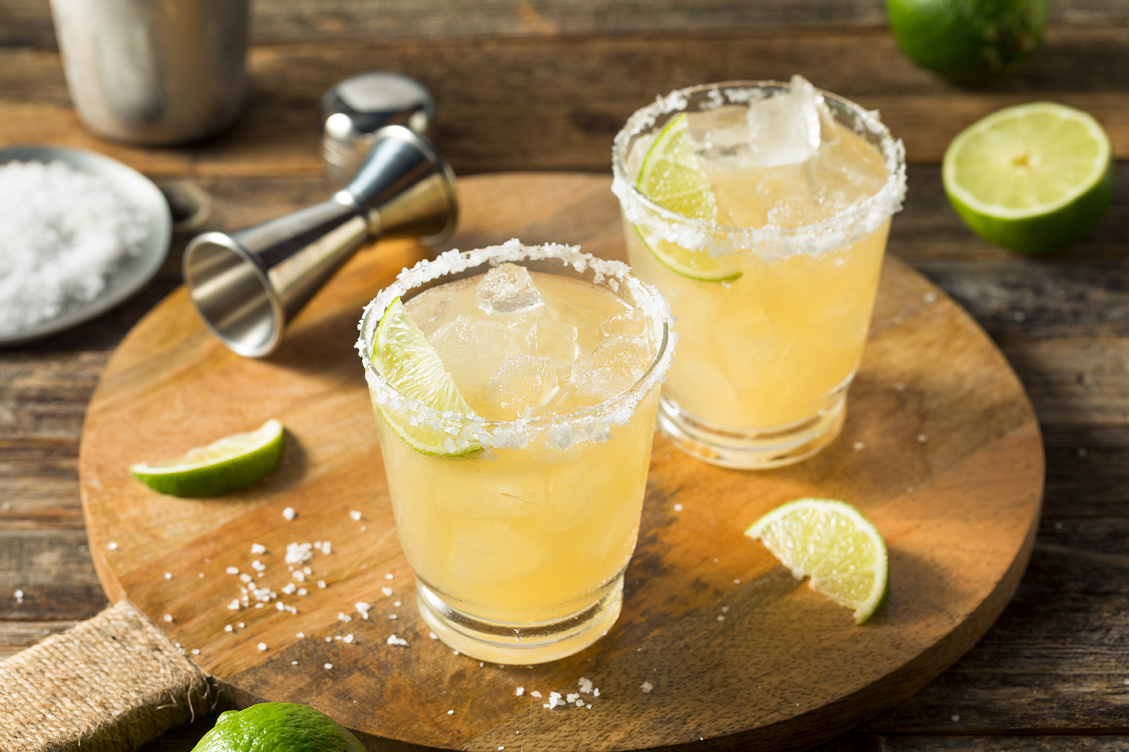 Margaritas with lime slices and cocktail tools